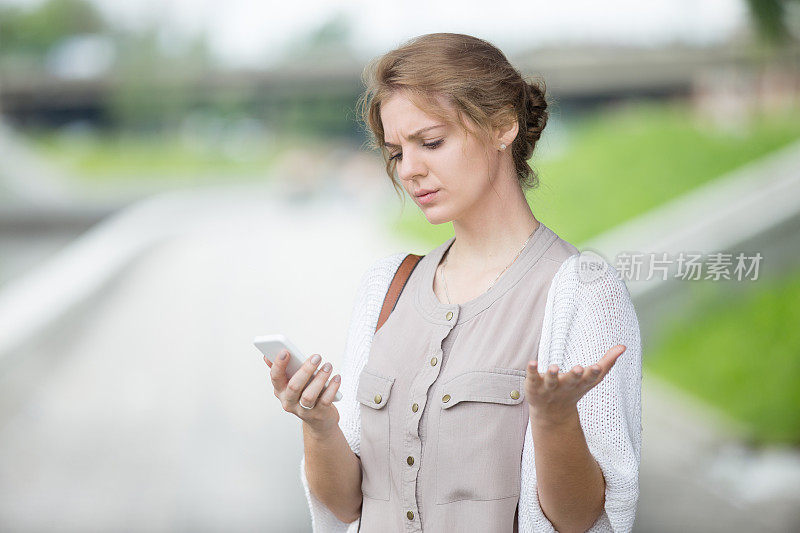 压力重重的女性在户外看智能手机屏幕的肖像
