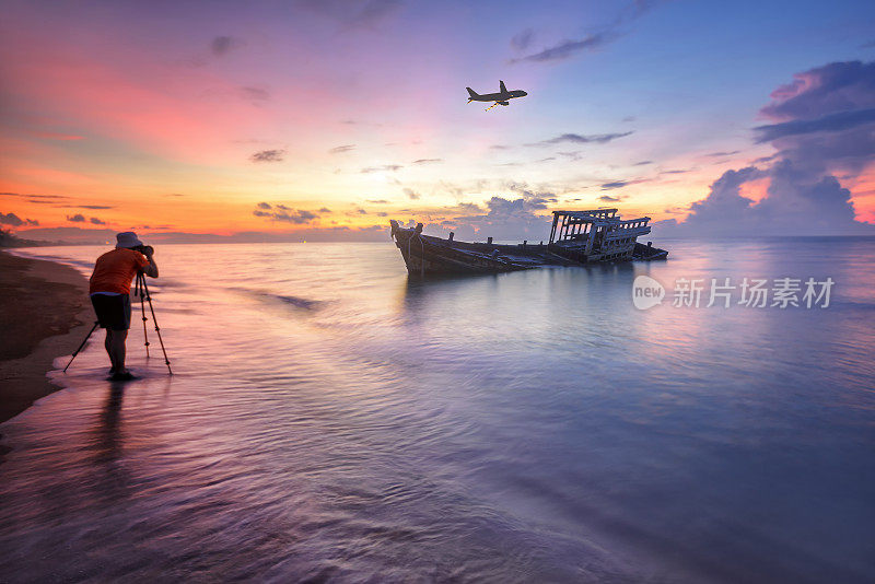 泰国乌塔堡机场海滩旁的剪影摄影师和失事的渔船。