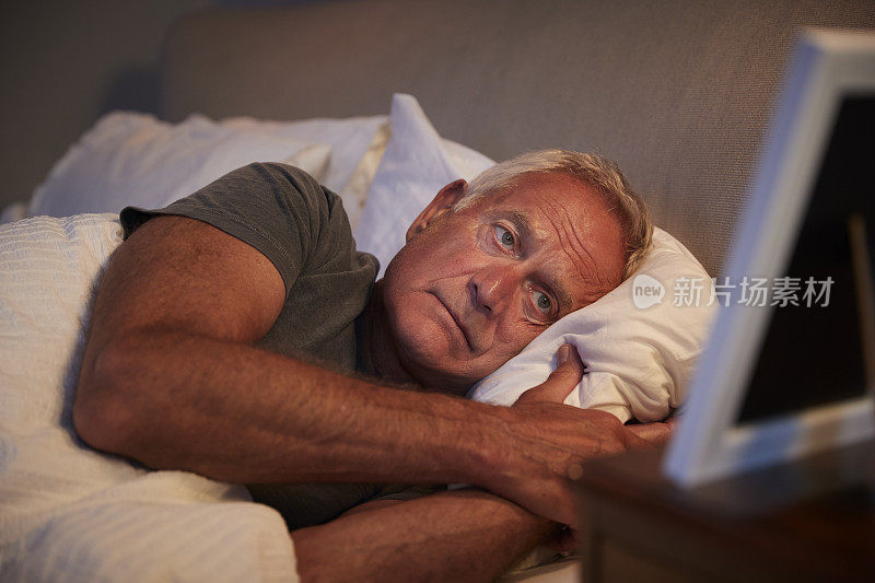 悲伤的老人躺在床上看相框