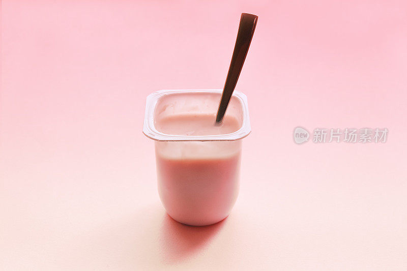 粉色背景的白色塑料杯草莓酸奶