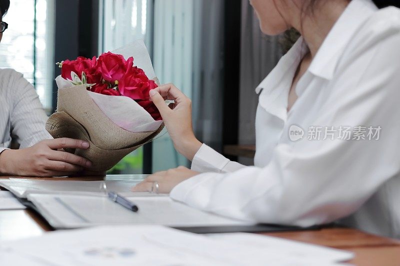 迷人的年轻亚洲女性在情人节接受办公室男友的一束红玫瑰的复古形象。职场爱情和浪漫的概念。