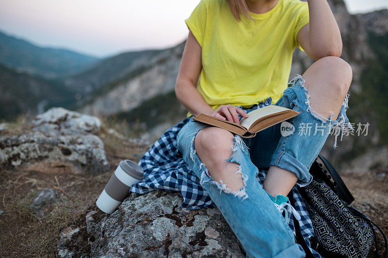 女孩坐在岩石山上，在山顶上放松，