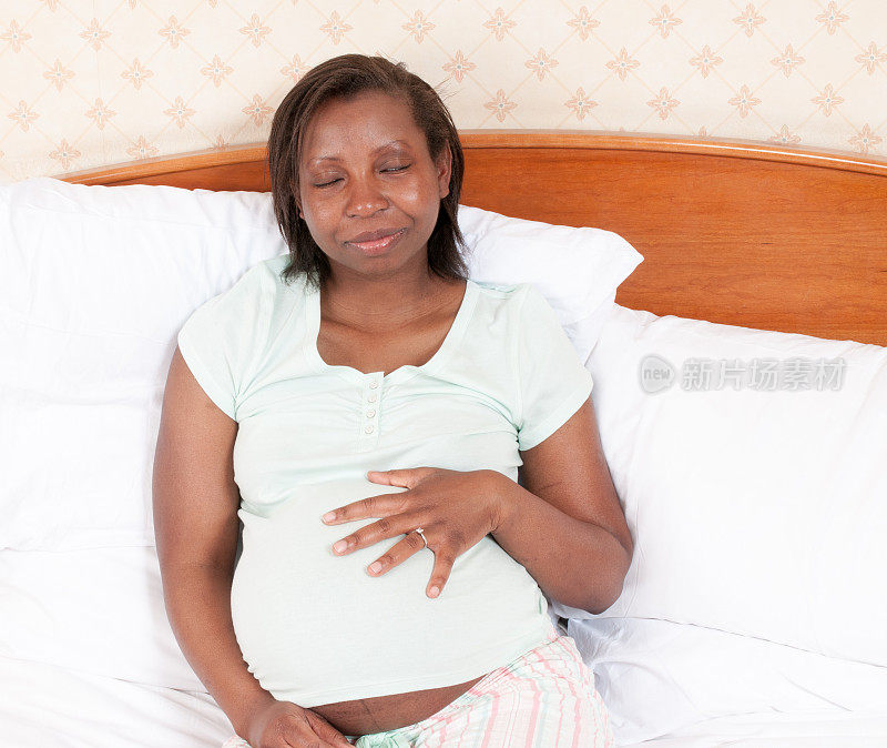 孕妇闭着眼睛触摸腹部