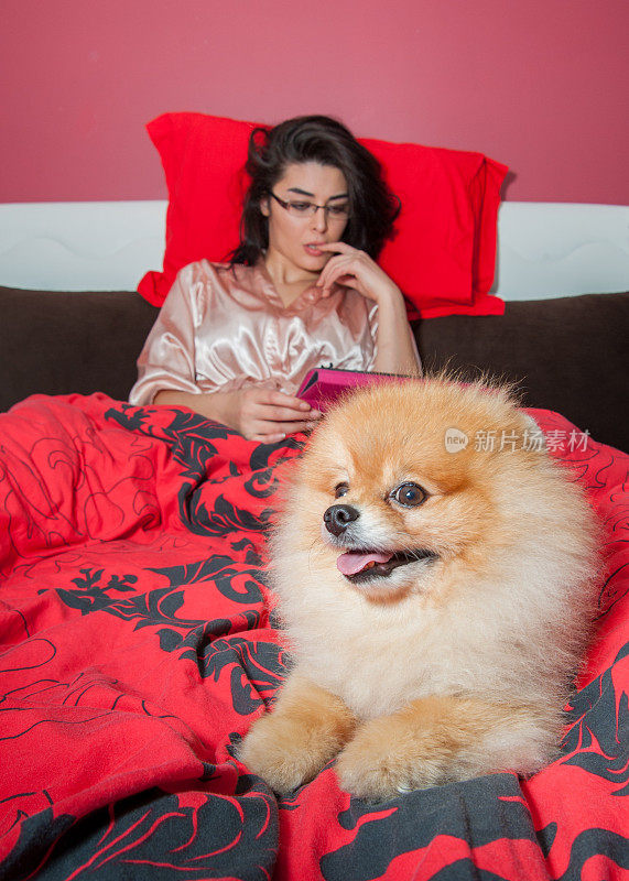 一个女人和她的博美犬在床上