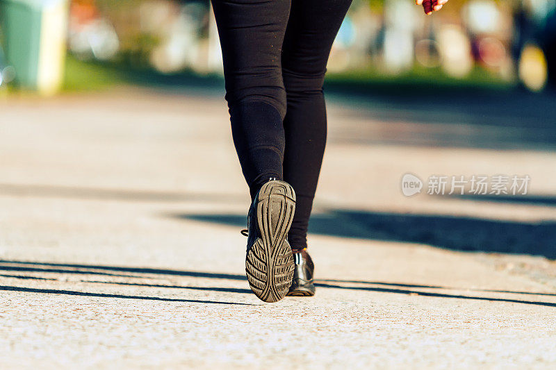 女人的腿与绑腿和运动鞋走在一条小路上