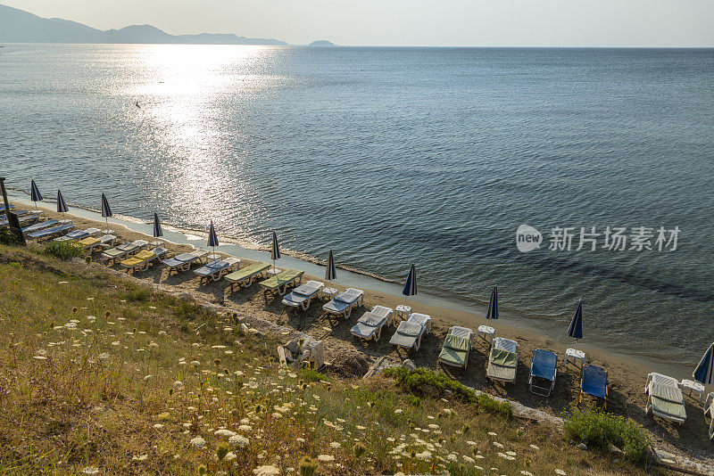 希腊的沙滩椅和阳伞。Zakinthos,贴水Sostis。在空旷的海滩上，一排带靠垫和阳伞的沙滩椅，在海龟岛(马拉松西)，清晨。GPS标记。