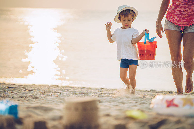 小男孩和他面目全非的妈妈在海滩上散步。