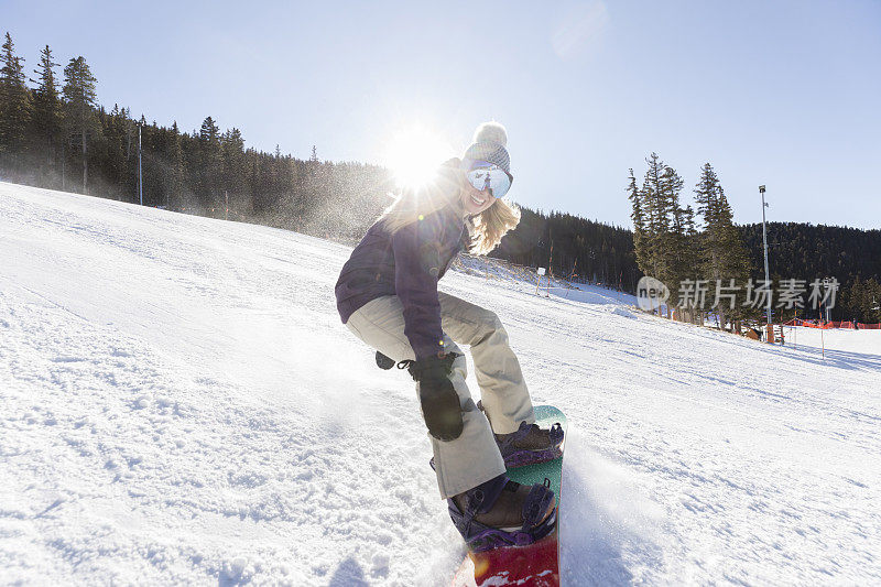 年轻女子用滑雪板从高山上滑下来