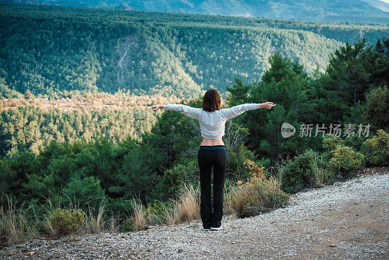 年轻的女性跑步者在晨跑前热身森林小径