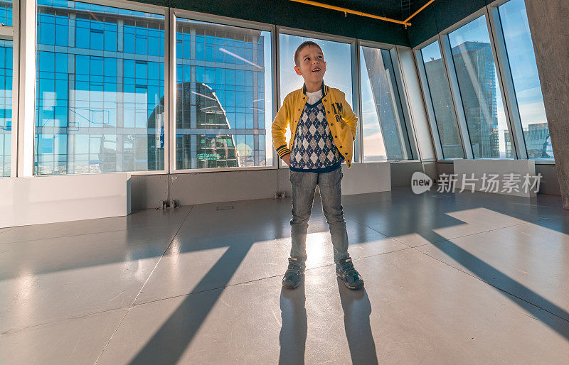 自信的男孩站在摩天大楼顶层