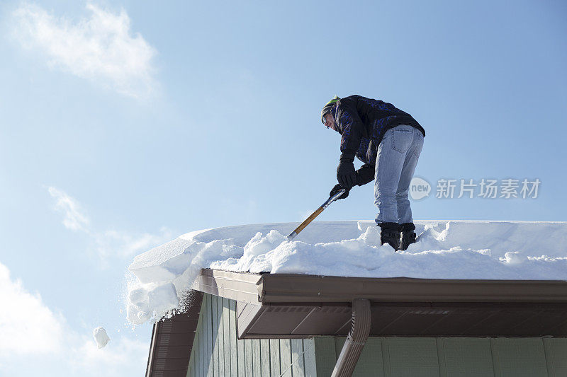 一名男子正在铲屋顶上的积雪