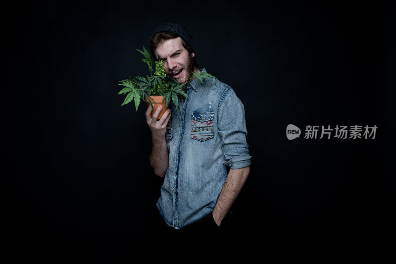 年轻的瘾君子和大麻植物站在一起