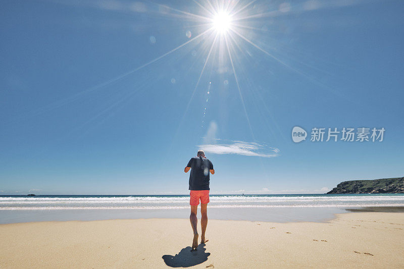 6月一个炎热阳光明媚的日子，康沃尔郡，一名男子正走向佩顿范德海滩的海边。