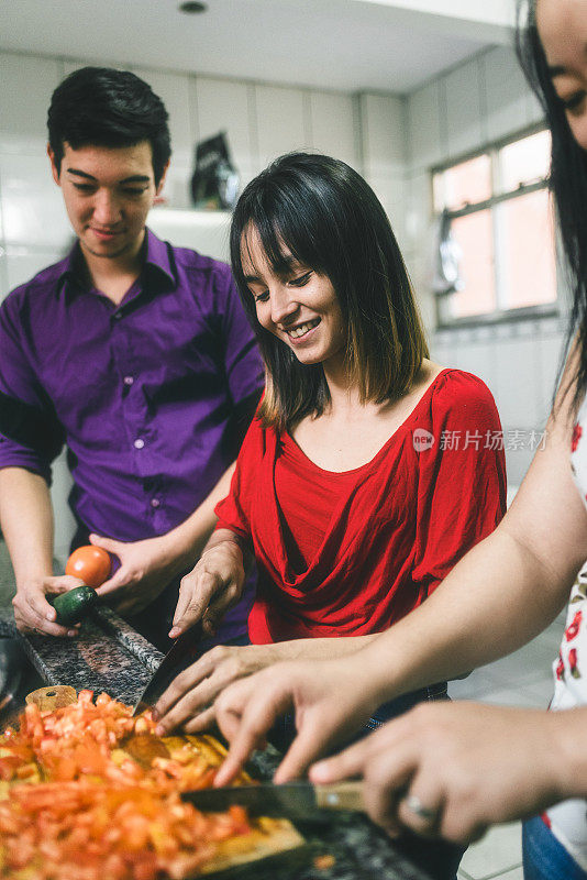 年轻的亚洲女性在厨房的水槽里切西红柿