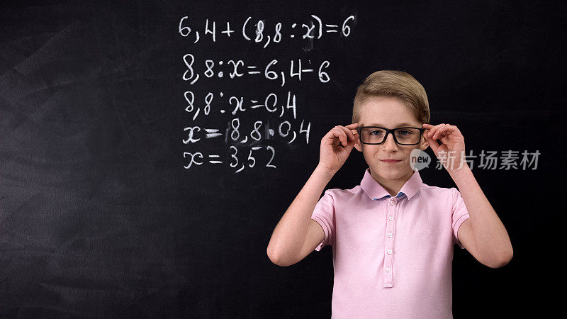 戴眼镜的男生靠着黑板做数学题