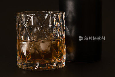 黑色的桌子上放着威士忌水晶杯