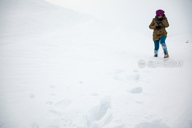 成年妇女穿着暖和的衣服在雪地上行走在农村