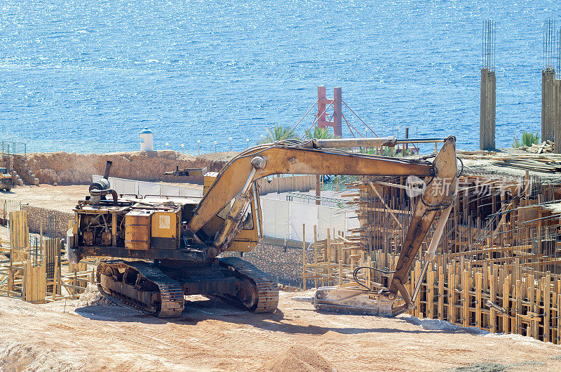 在海边的一个建筑工地，挖掘机和液压手提钻