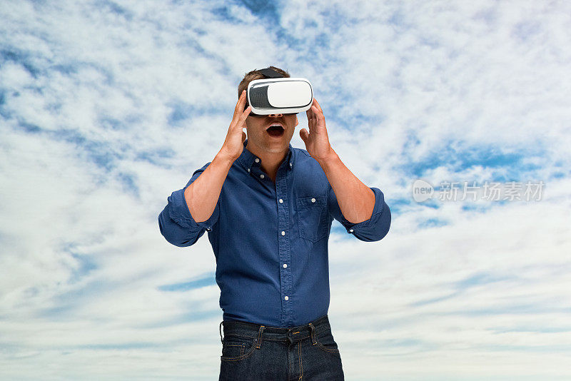 白人年轻男性站着，使用虚拟现实模拟器