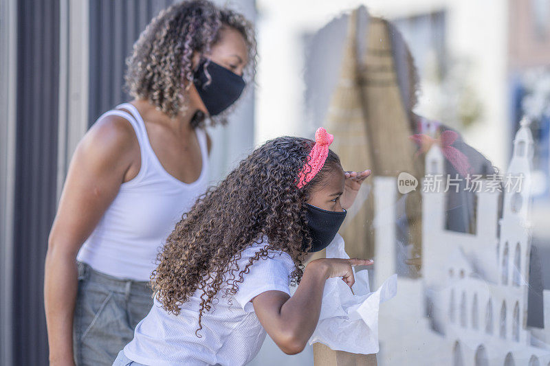 非裔美国母亲和女儿戴着面具在市中心购物