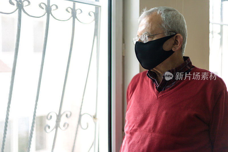 老人戴着防护口罩在家看窗外