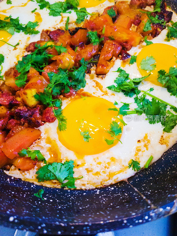 Shakshouka——用孜然调味的鸡蛋、番茄和香菜——在炉子上的煎锅里烹饪