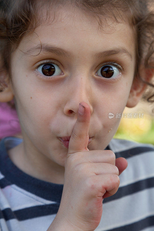 一个小女孩把手指放在嘴唇上的特写