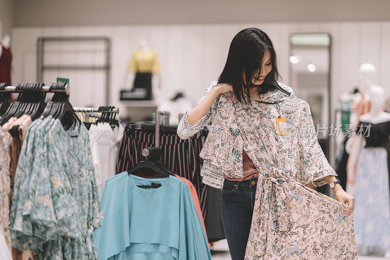 亚洲华人女性在服装零售店购物和浏览