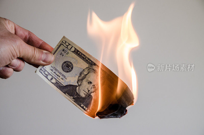 手里拿着一张正在燃烧的20美元钞票