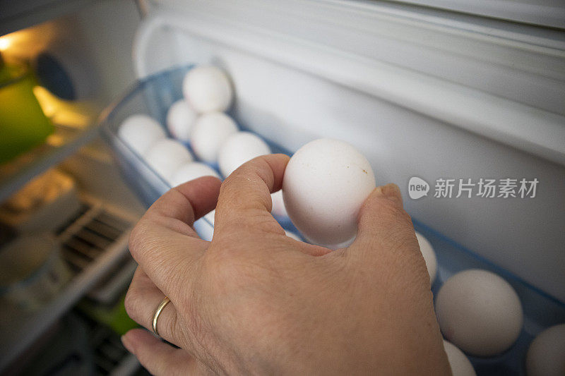 女人从冰箱门里拿出鸡蛋