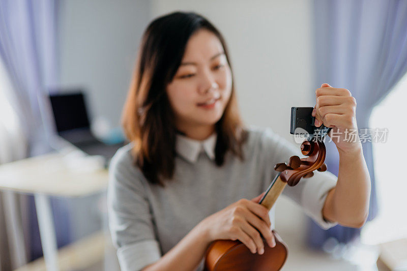 年轻的亚洲女小提琴家正在为她的小提琴调音