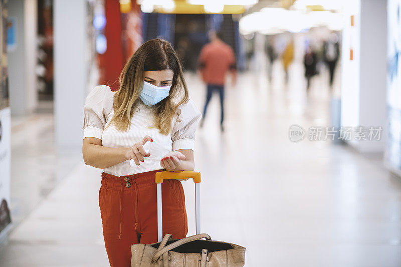 年轻女子戴防护口罩在机场为手消毒