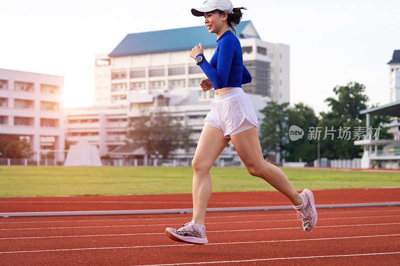 年轻的健身女跑步者早上在城市体育场的跑道上慢跑锻炼。女运动员在市体育场锻炼以保持身体健康