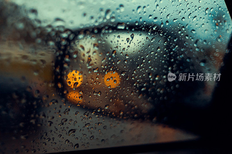 模糊的雨滴落在汽车玻璃的背景上，水滴落在司机身旁的车窗上。