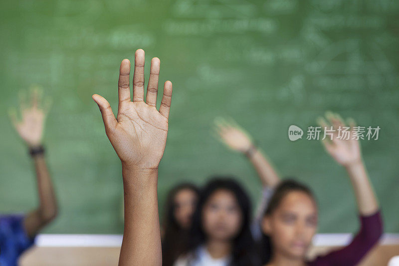 多元文化的青少年举手坐在教室里