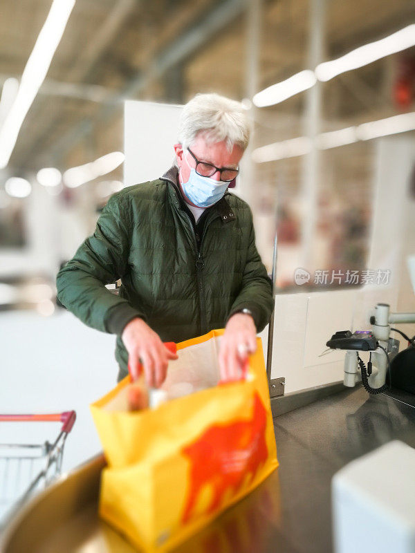 戴着防护口罩的老人在超市结账处