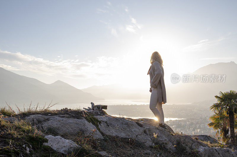 女人走在岩石小山之上的湖和山