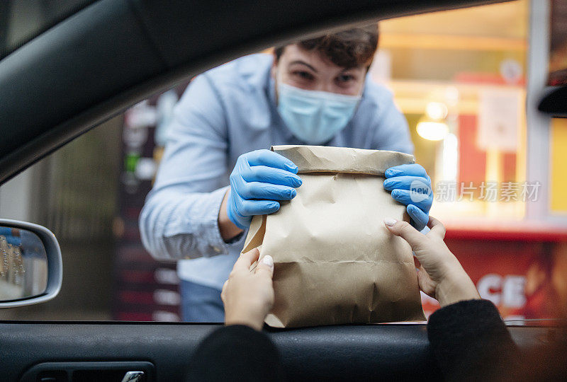 男餐厅工作人员在餐厅前给顾客送包装好的食物。