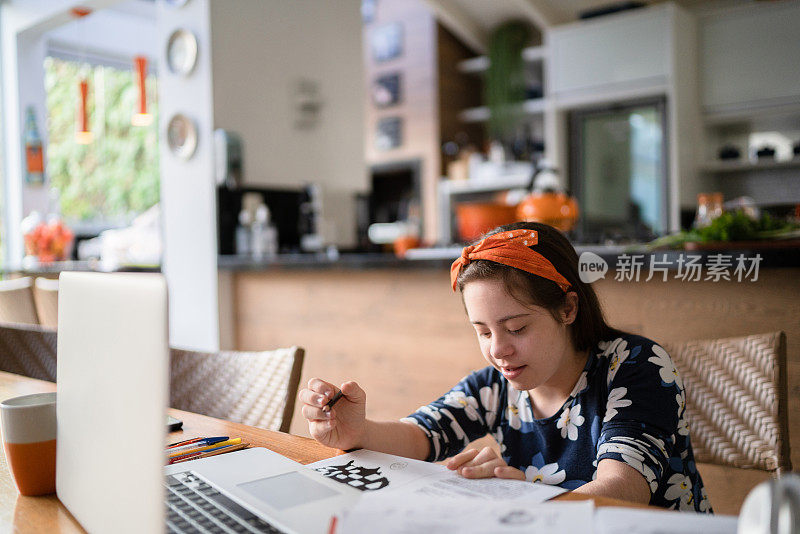 有特殊需要的女孩在家里用笔记本学习