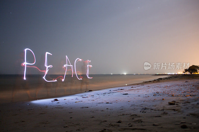 一个和平的词使它在夜晚在海滩上的一盏灯