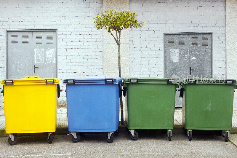 人行道旁一排供回收用的彩色垃圾桶。