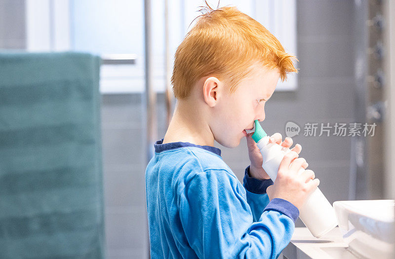 红发小男孩用生理盐水喷鼻剂清洁和排空鼻子