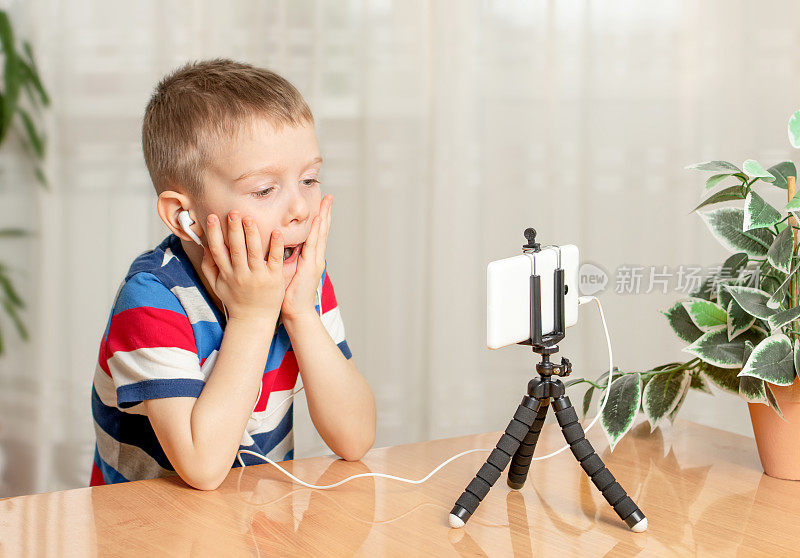 一个戴着耳机的男孩专心地看着手机。孩子们对电子产品的上瘾。学龄前儿童的在线学习