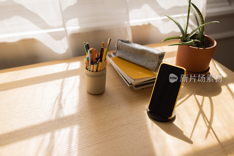 现代工作区:木桌上的笔记本和智能手机