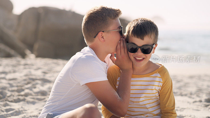 一个小男孩在沙滩上对着弟弟耳语的镜头
