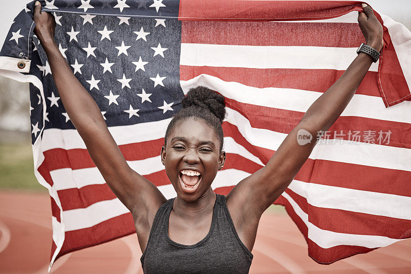 一名年轻的女运动员拿着一面旗子跑步庆祝胜利