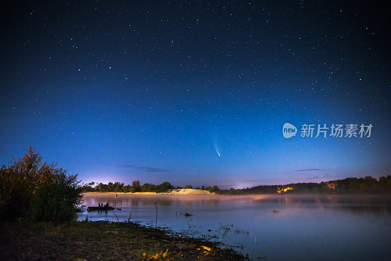 夜空中的彗星。夏天的星空。天上的星星。美丽的夜晚景观。长时间的曝光。观念摄影。雾气笼罩着水面。大气的格局。晨光。