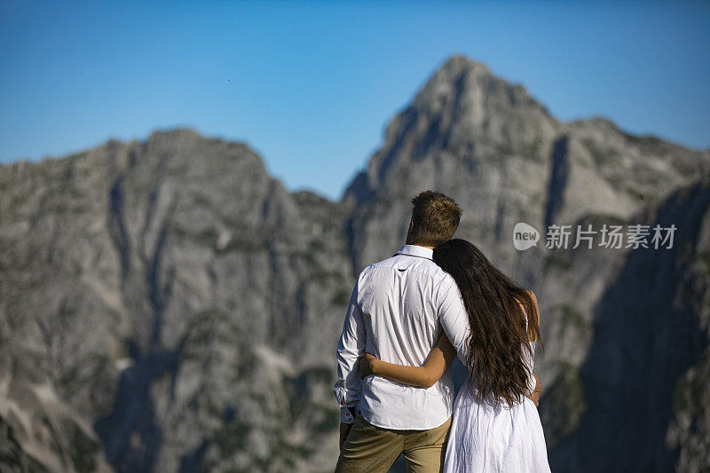 年轻的情侣拥抱在一起，在山上看风景