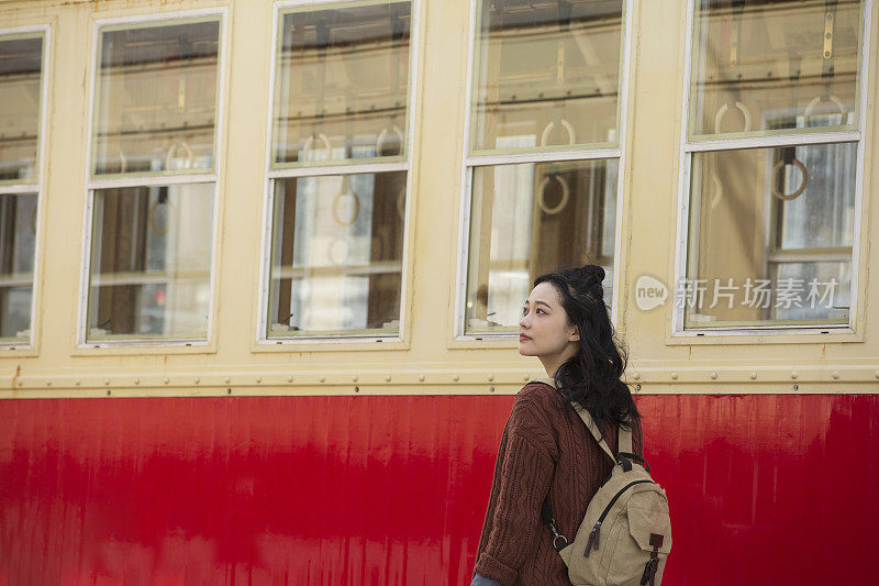 年轻的女游客站在一张缓慢移动的旧有轨电车照片旁边