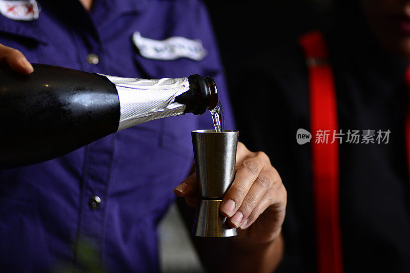 在深色背景的高级酒吧里，调酒师正在准备水果饮料。